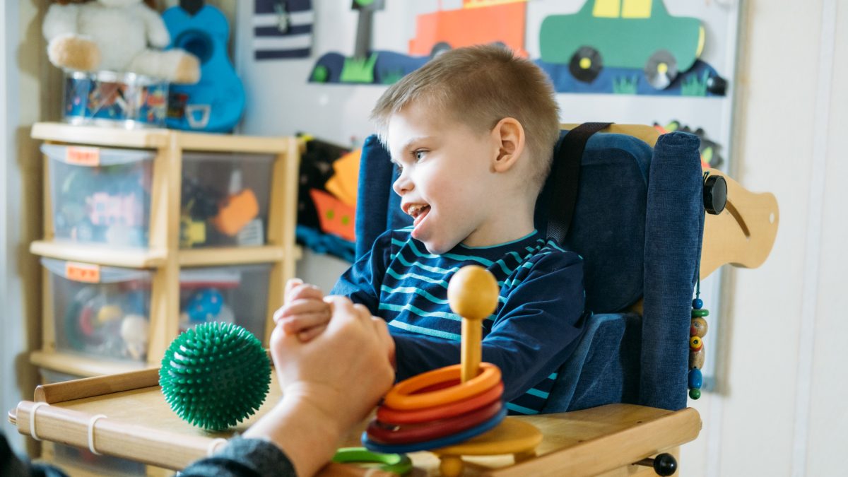 Young boy with cerebral palsy in high chair. 